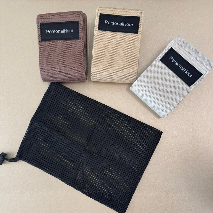 Set of non-slip Pilates bands in beige, mauve, and dark gray/black fabric loops.