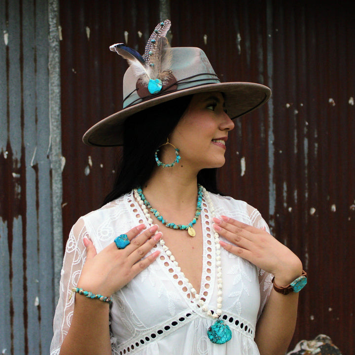 Turquoise beaded collar necklace with coin charm and matching hoop earrings on model