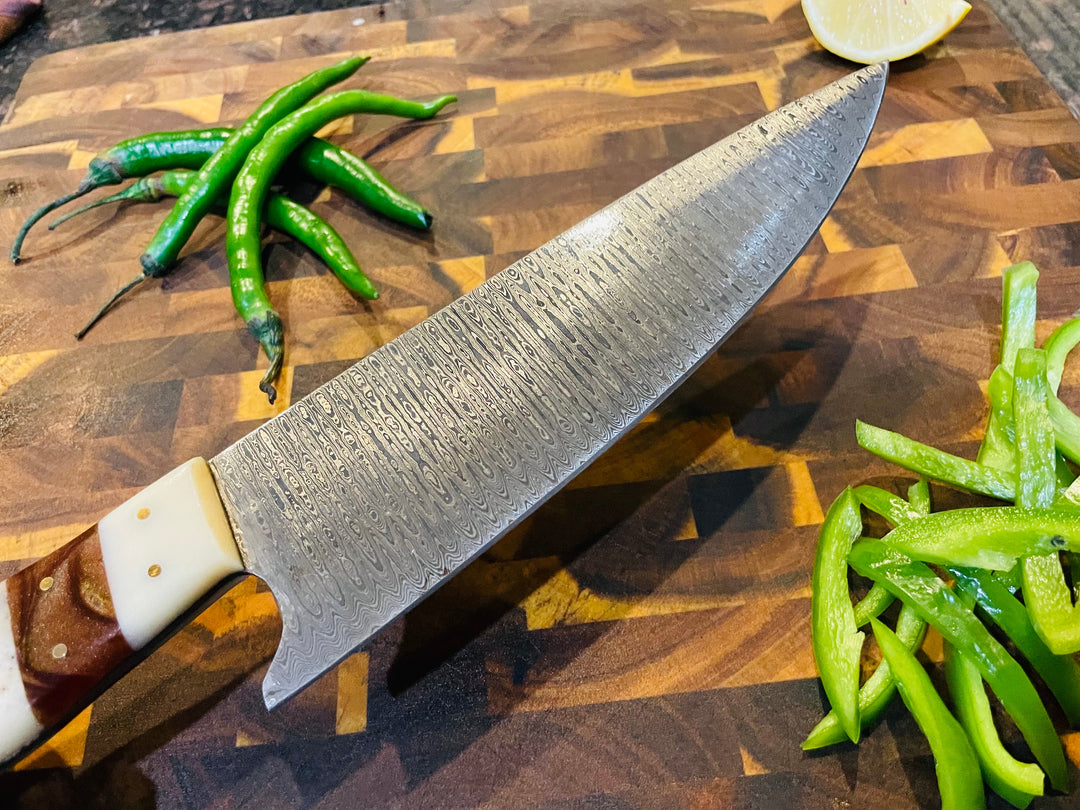 Damascus-style chef knife side view with wavy blade pattern and wood-and-cream handle