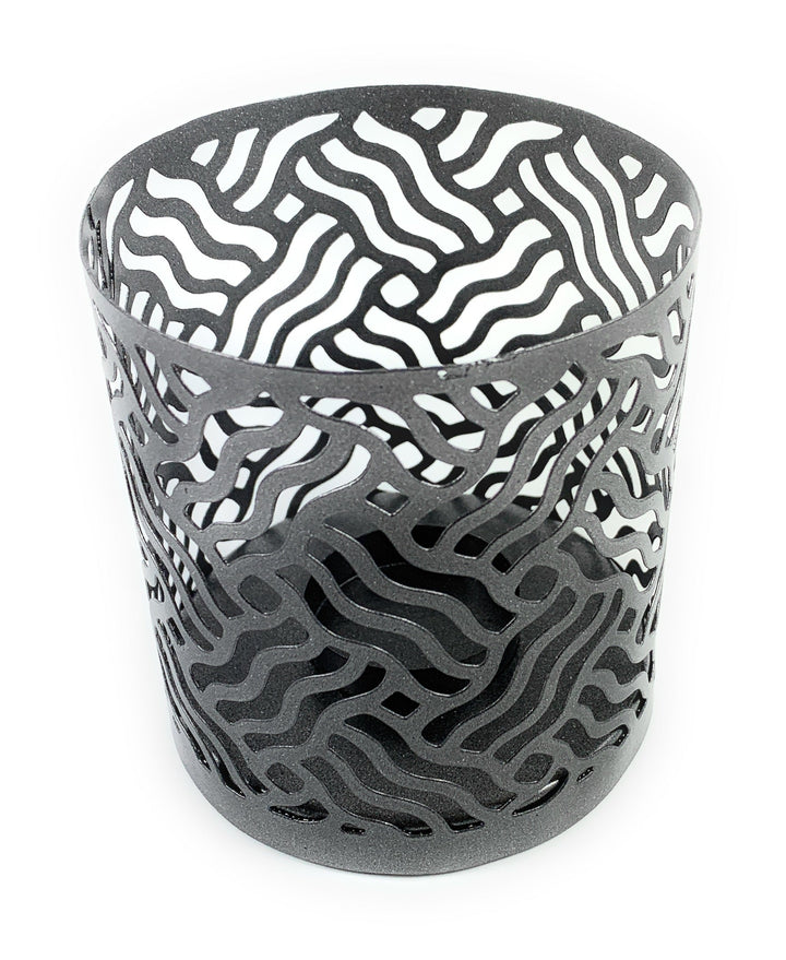 Grey perforated metal votive candle holder with curved cutout swirls, cylindrical