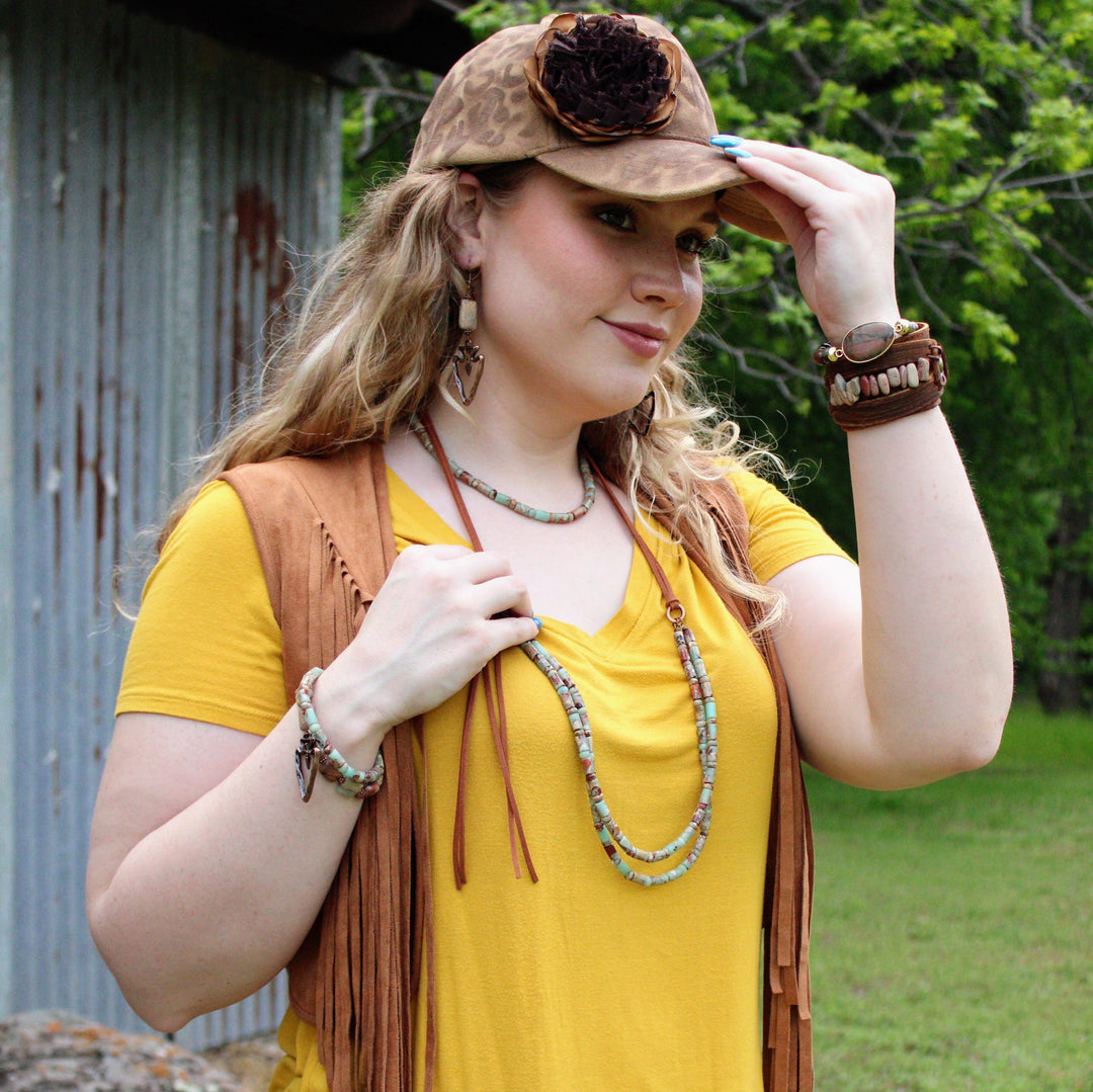 Beaded collar necklace with turquoise accents worn with a fringe vest and layers