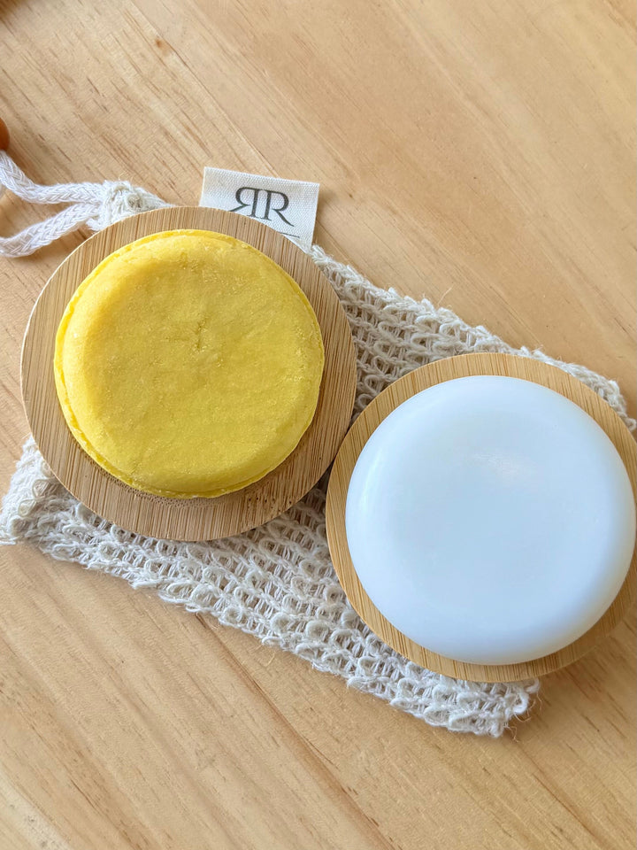 Solid conditioner bar halves in a wooden dish: yellow top and white base round