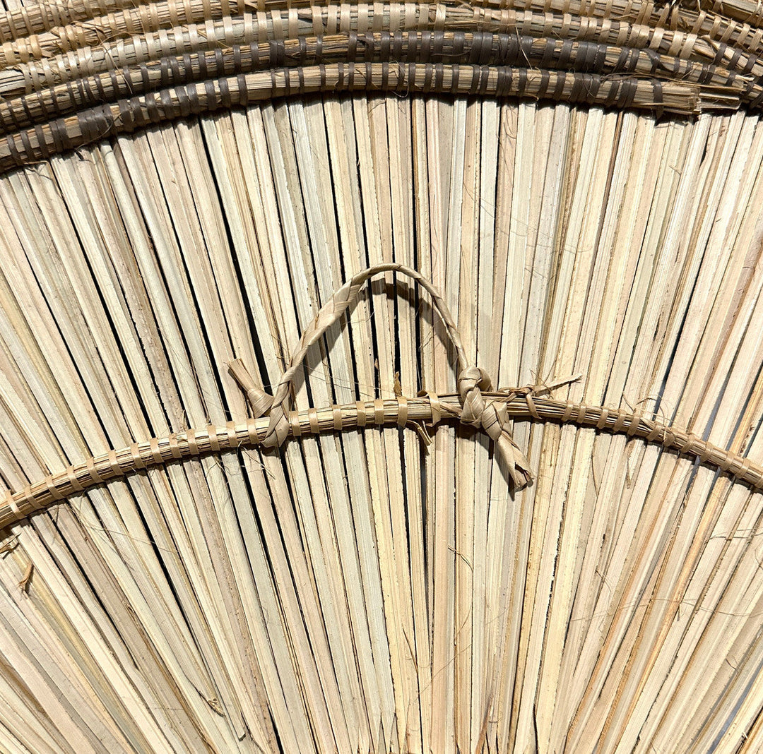 Close-up of woven rattan sunburst wall plate with tied knot detail on rim