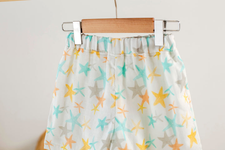 Close-up of starfish muslin shorts: elastic waistband with gathered fabric, multicolor print