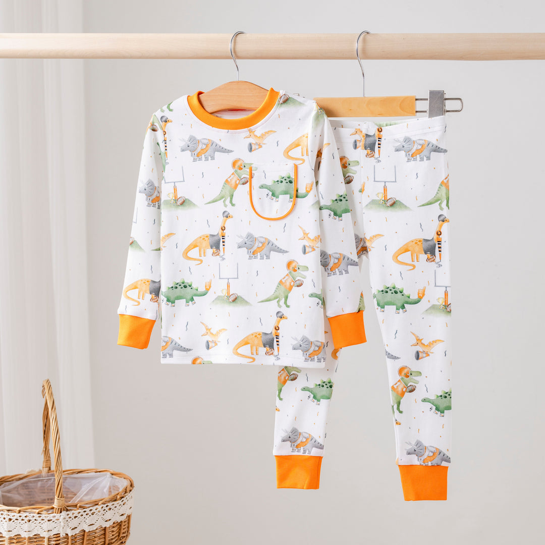 Kids pajama set in white with colorful dinosaur prints and orange cuffs