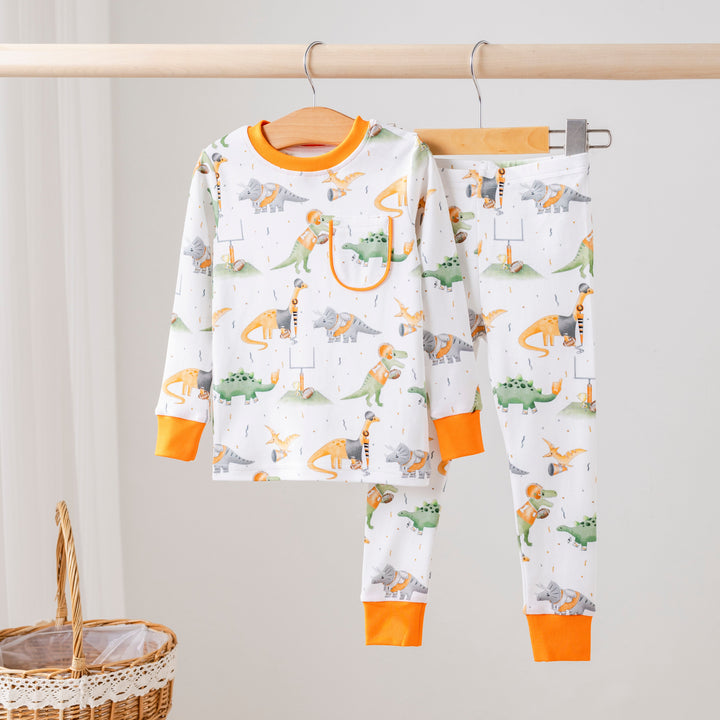 Kids pajama set in white with colorful dinosaur prints and orange cuffs