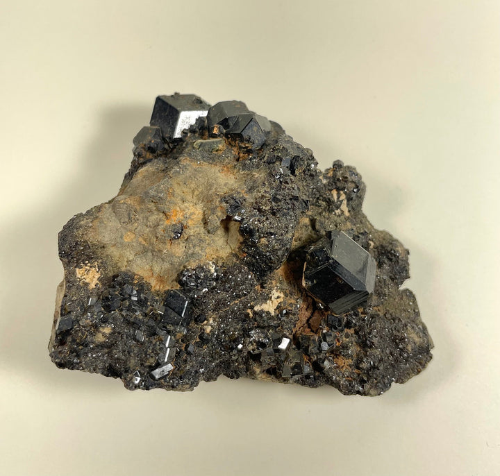 Black metallic crystal cluster with golden tan pockets on rock