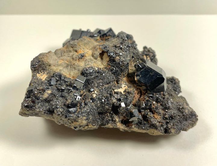 Dark metallic garnet and cube crystals on gray-brown rock matrix