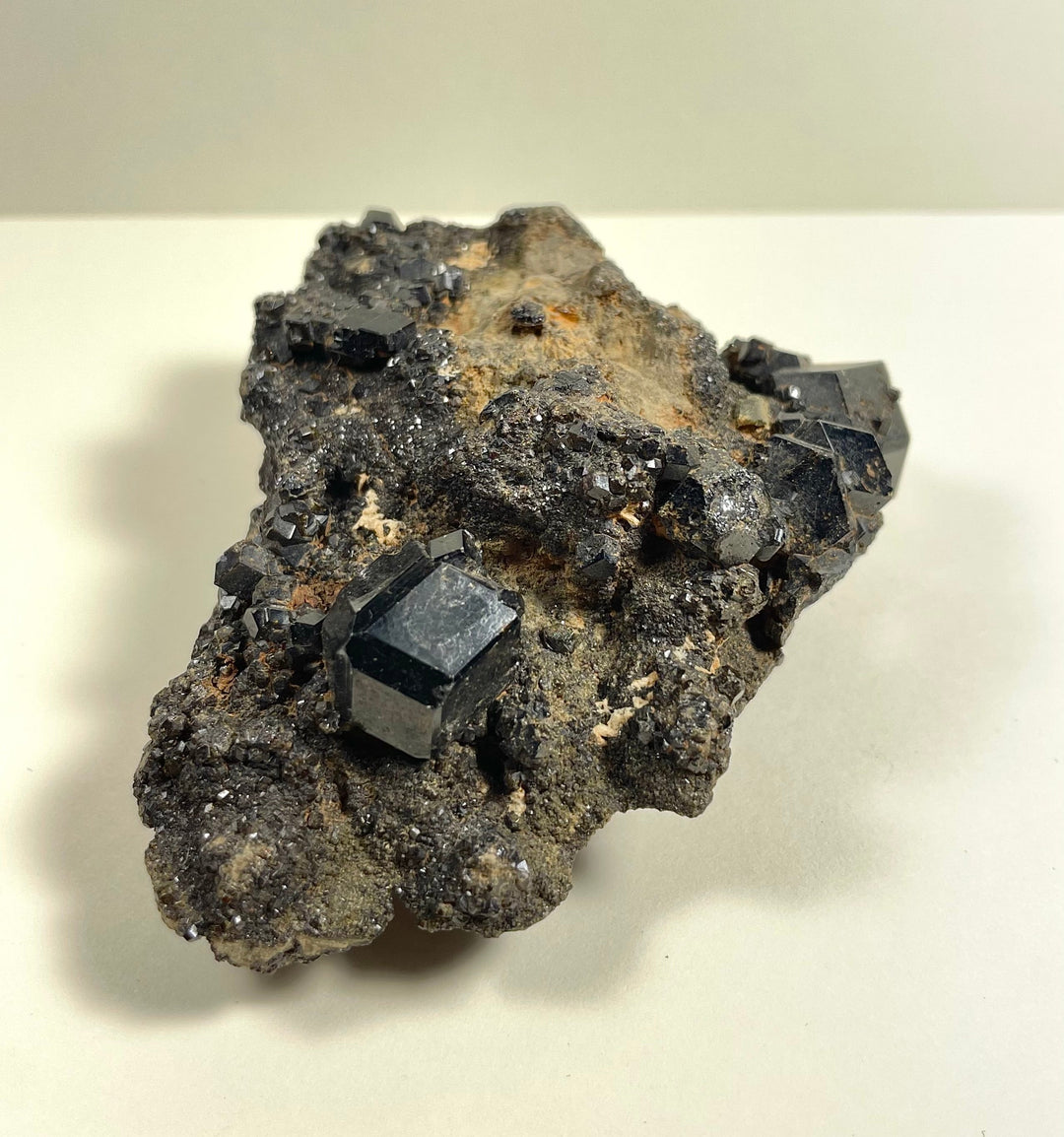 Metallic black cube-like crystals embedded in gray rock with tan areas