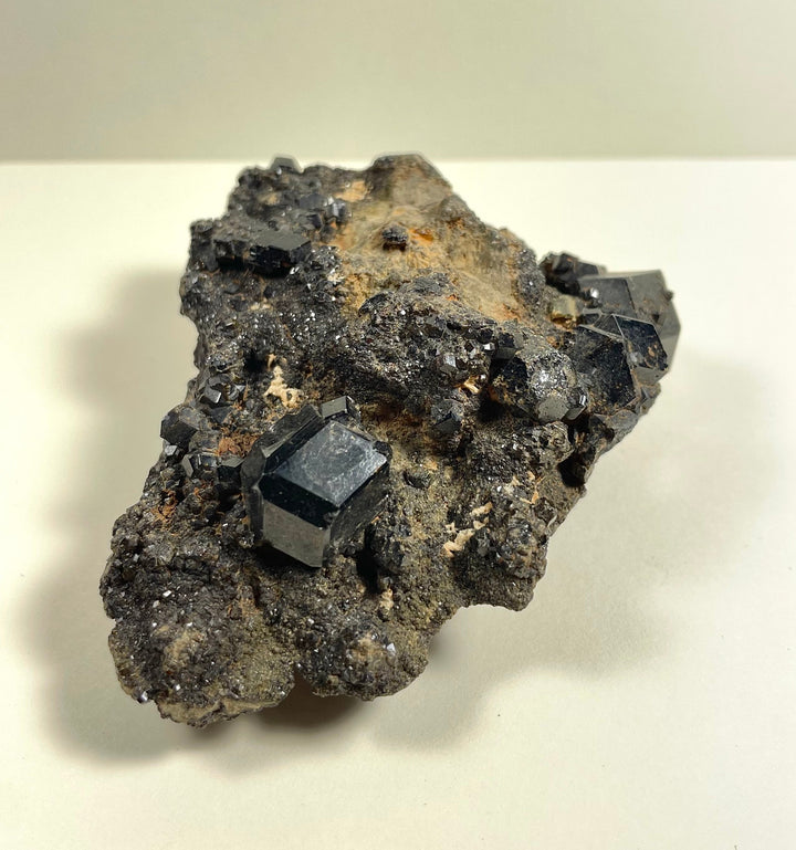 Metallic black cube-like crystals embedded in gray rock with tan areas