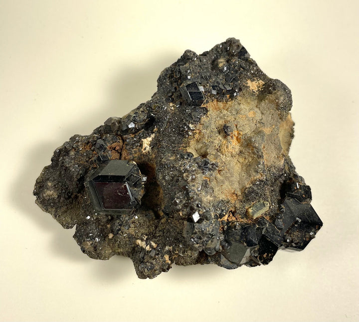 Garnet cluster with deep black crystal cubes on dark rock matrix