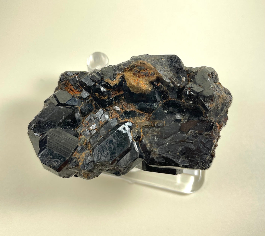 Melanite garnet cluster mineral on silver-toned display base, dark crystals