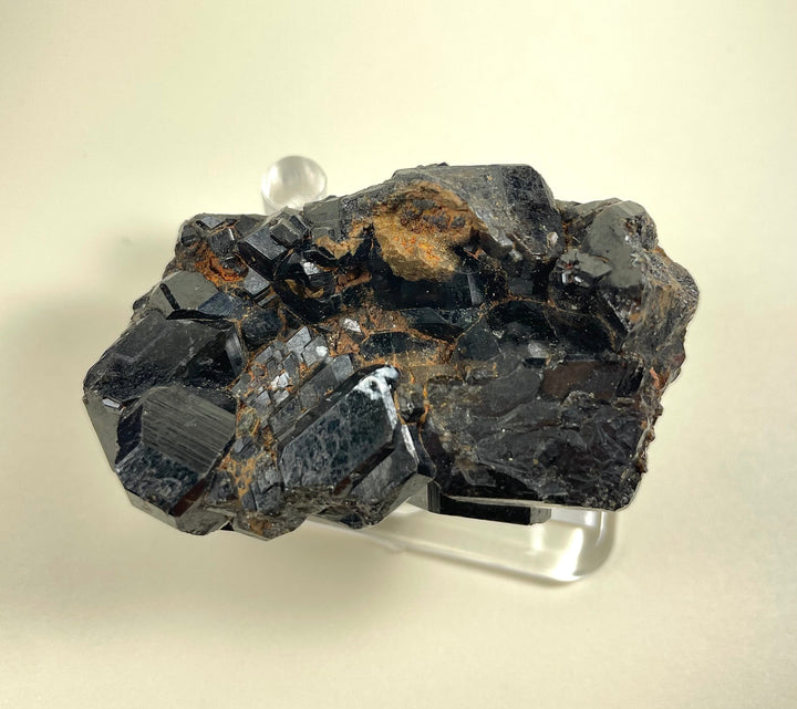 Melanite garnet cluster mineral on silver-toned display base, dark crystals