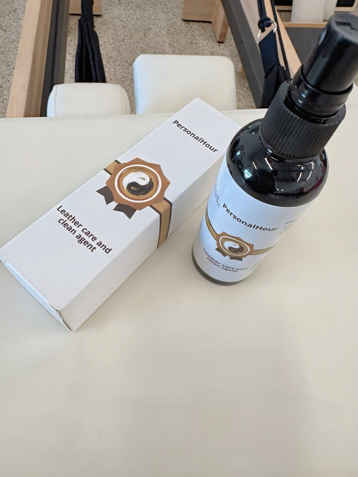 Leather care spray bottle beside closed white carton on workout bench