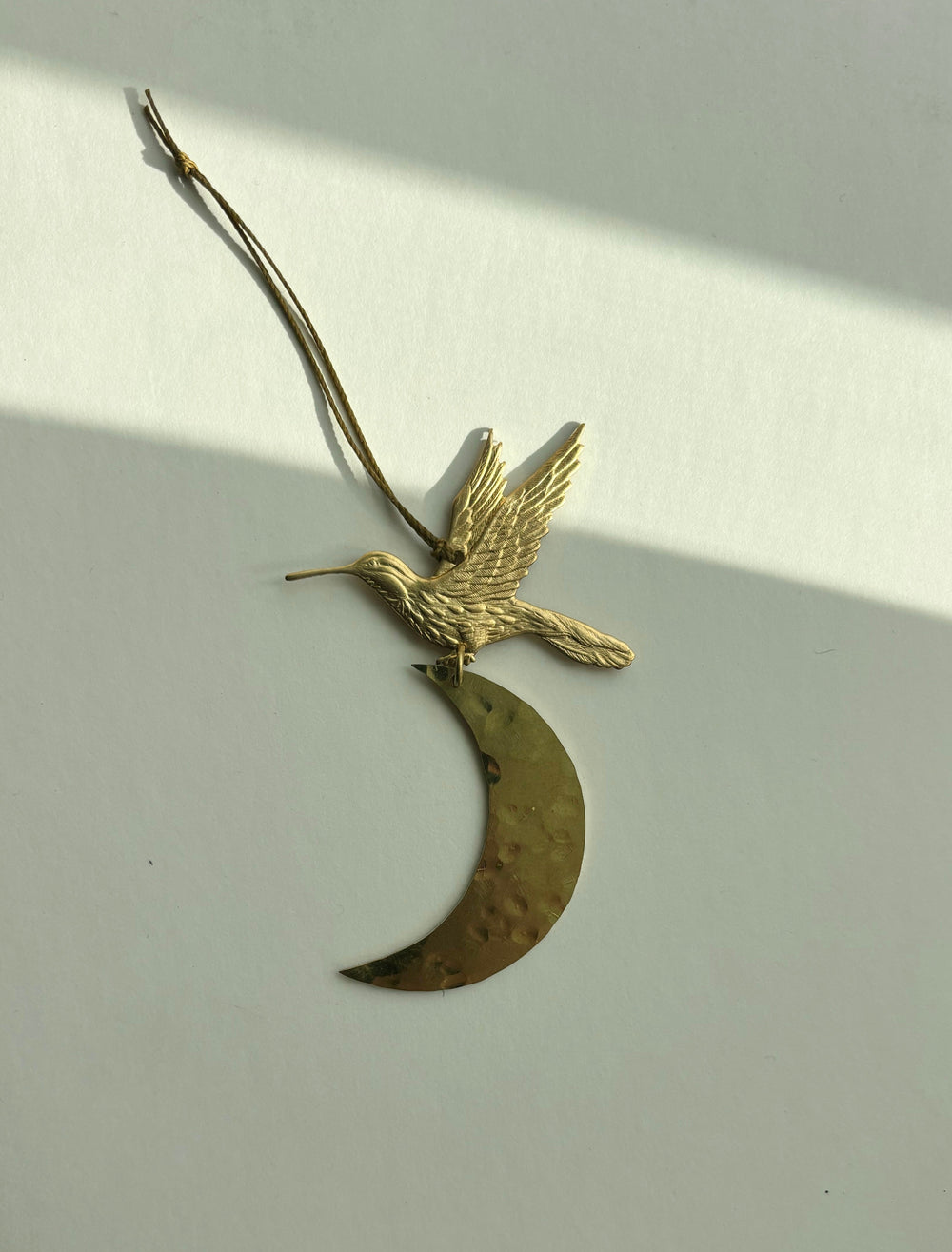 Gold bird and crescent moon ornament with hanging twine loop, side view