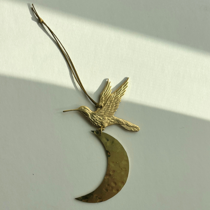 Gold crescent moon ornament with flying bird, hanging on twine loop