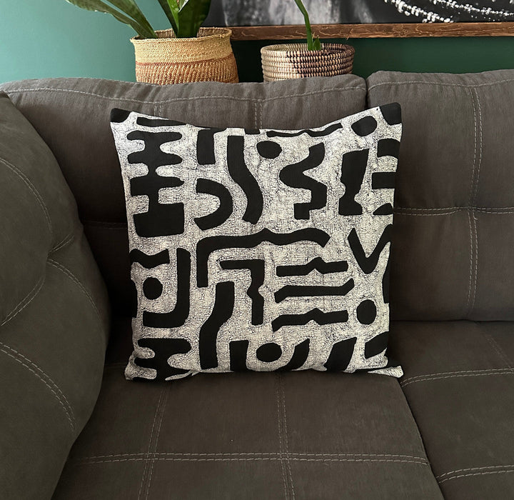 Black-and-white bogo marks pillow cover on dark sofa