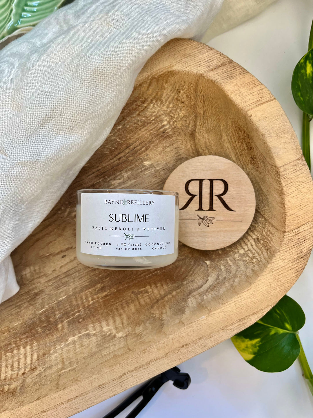 Coconut soy candle with wood lid and label in clear glass jar on tray
