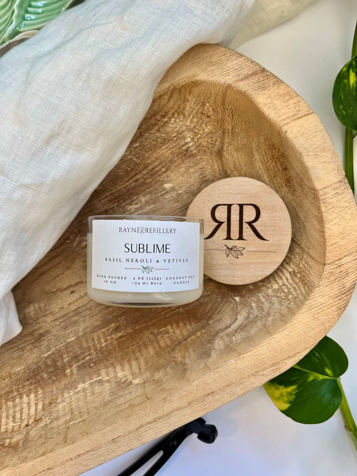 Coconut soy candle with wood lid and label in clear glass jar on tray
