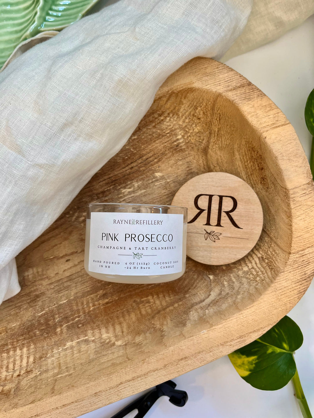 Pink Prosecco coconut soy candle in white jar with circular wooden lid on tray