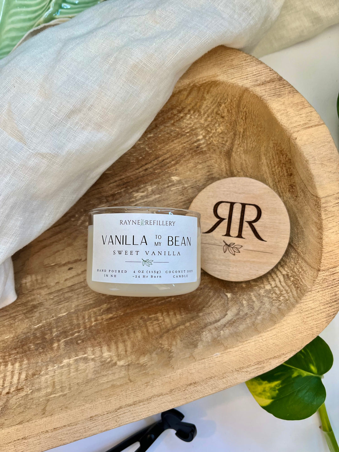 Vanilla coconut soy candle with white jar and engraved wooden lid on wooden tray