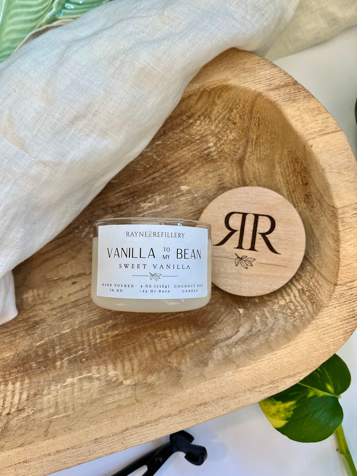 Vanilla coconut soy candle with white jar and engraved wooden lid on wooden tray