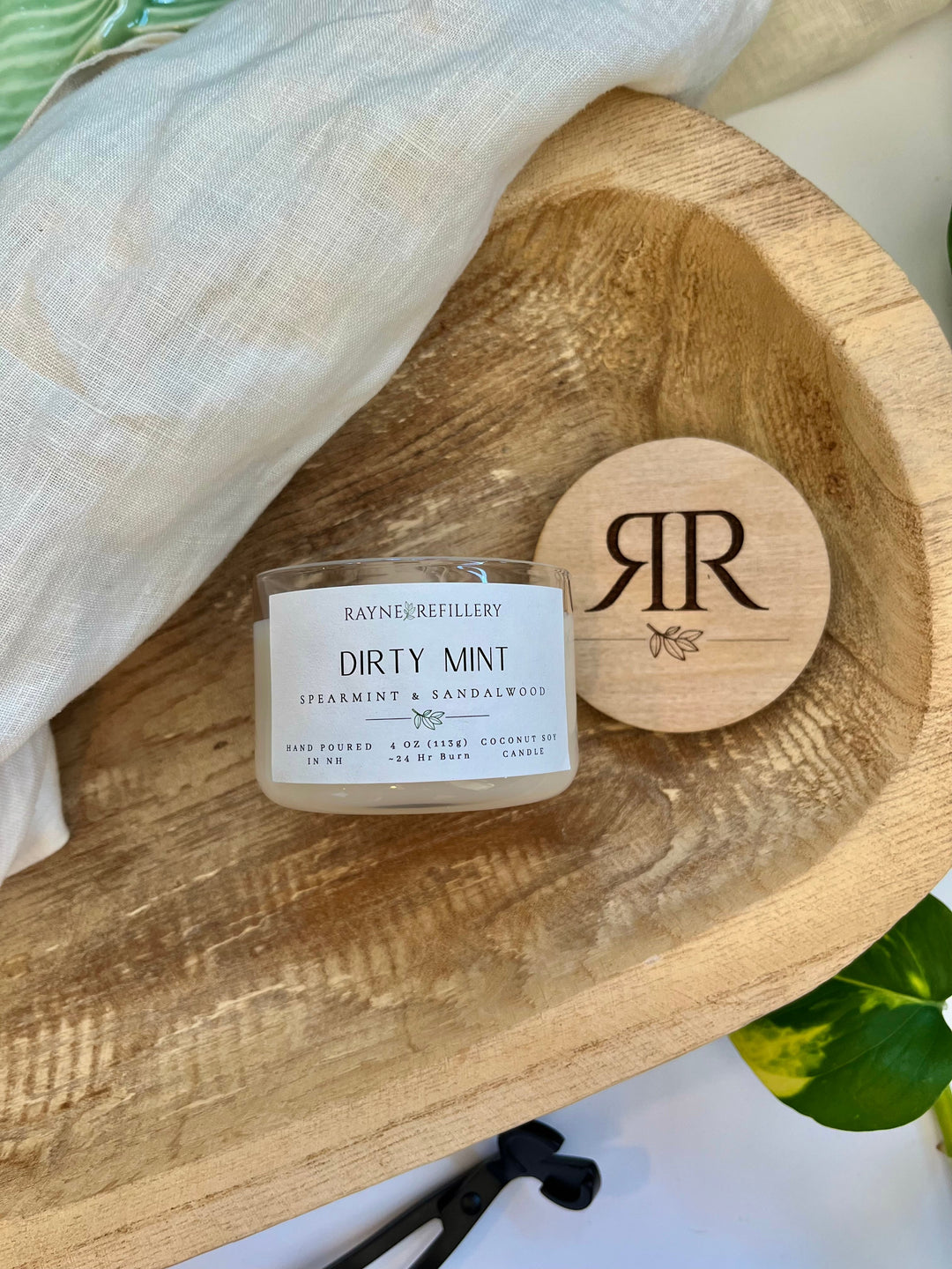 Coconut soy wax candle in clear glass jar with wooden lid, close-up of label