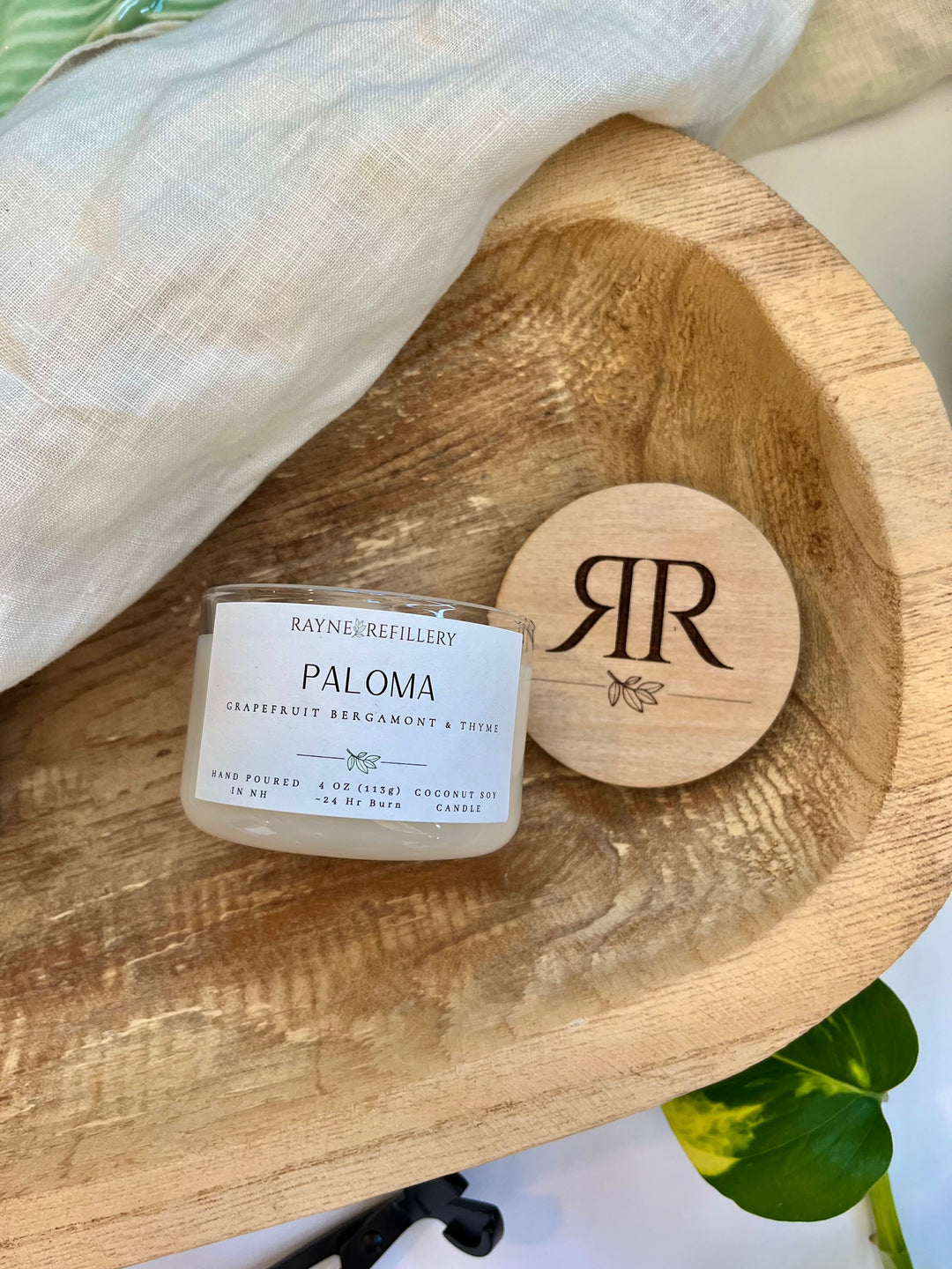 Coconut soy candle in white glass jar with wood lid on a rustic wooden tray with brand emblem