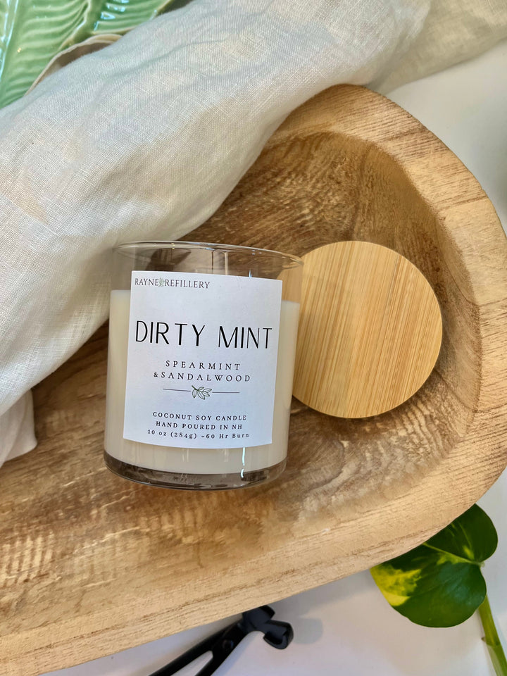 Coconut soy wax candle in clear glass jar with wooden lid on a wooden tray