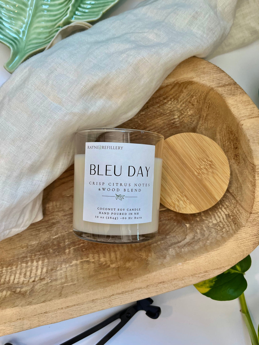Coconut soy candle in white glass jar with wooden lid on round wooden serving tray