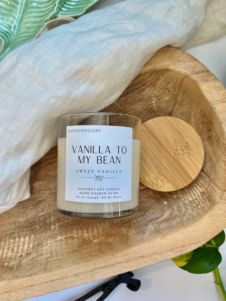 Vanilla coconut soy candle in white jar with wooden lid on rustic wooden board