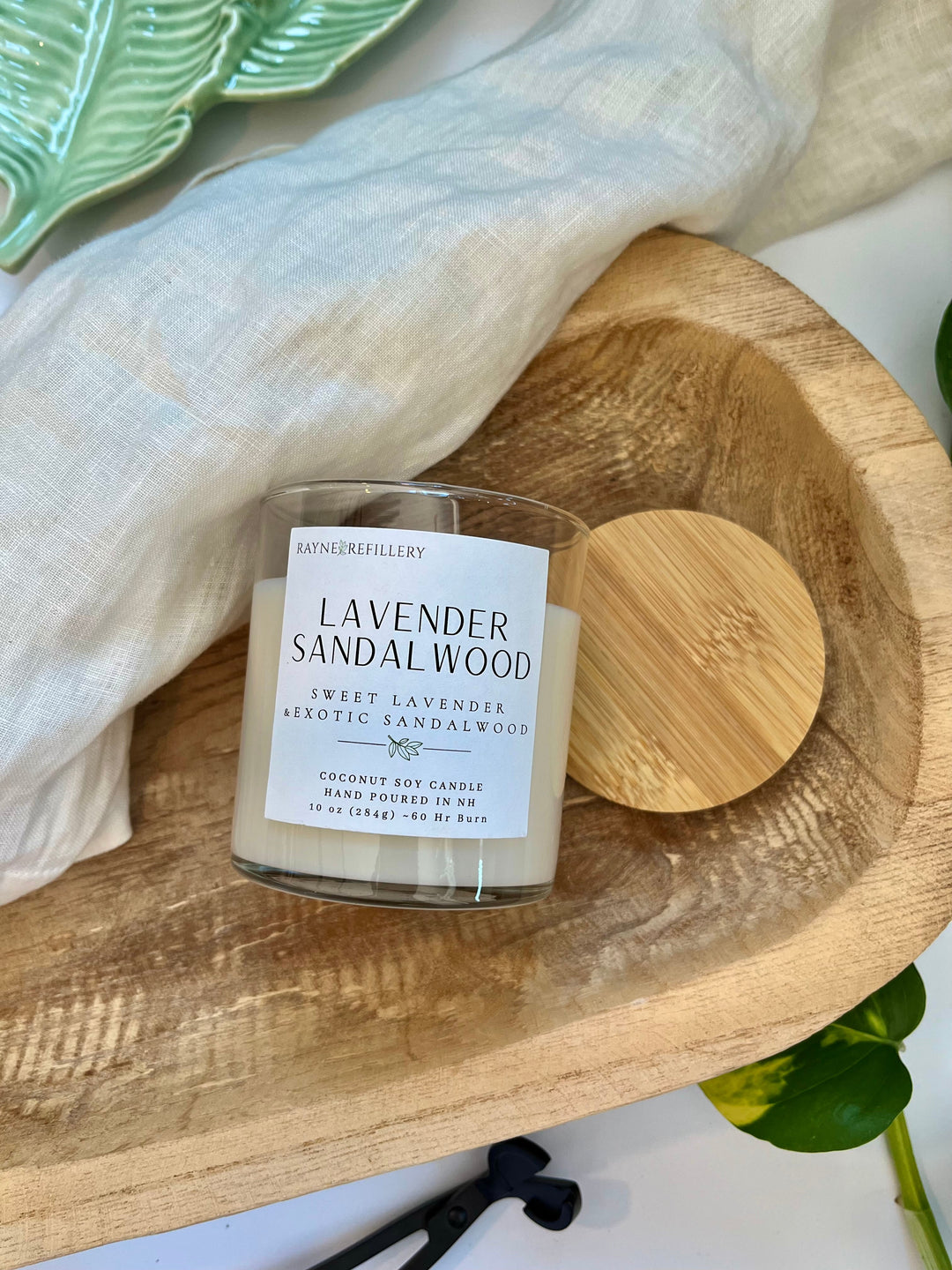Lavender sandalwood candle in white jar with wooden lid on circular wood base