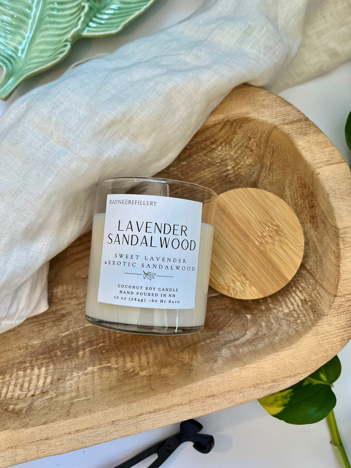 Lavender sandalwood candle in white jar with wooden lid on circular wood base