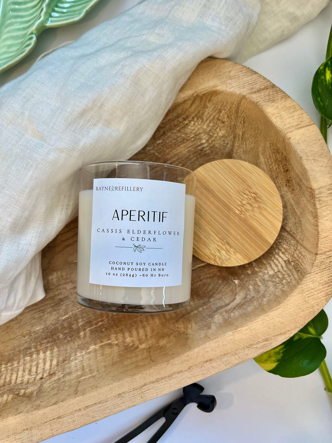 White coconut soy candle jar with wooden lid on round wood tray, printed label
