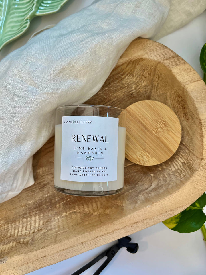 Coconut soy candle in clear glass jar labeled RENEWAL with wooden lid