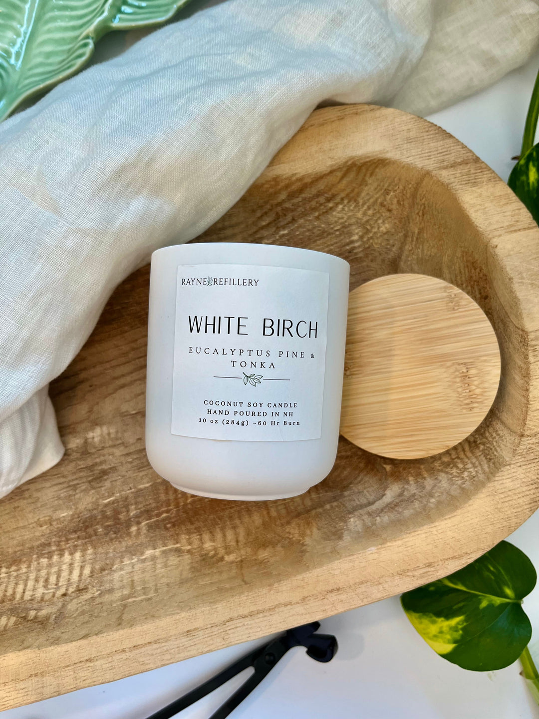 White Birch candle in white glass jar with wooden lid on oval wooden tray