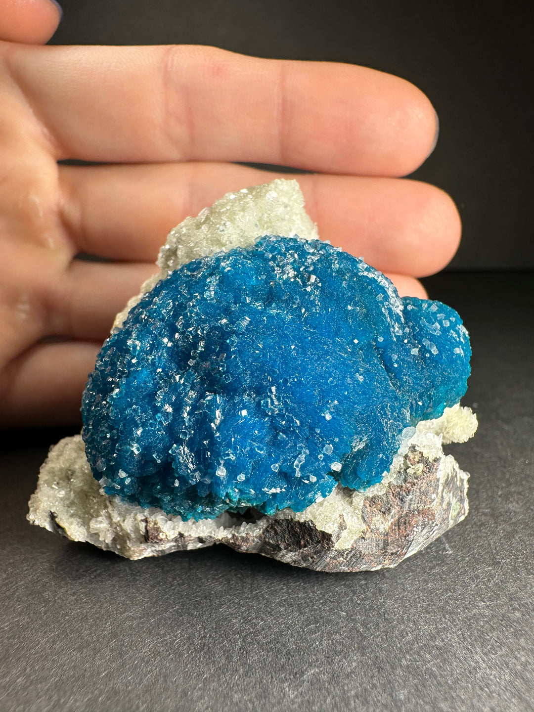 Blue cavansite and stilbite matrix mineral specimen held in hand, close view