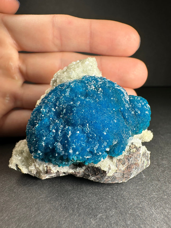 Blue cavansite and stilbite matrix mineral specimen held in hand, close view