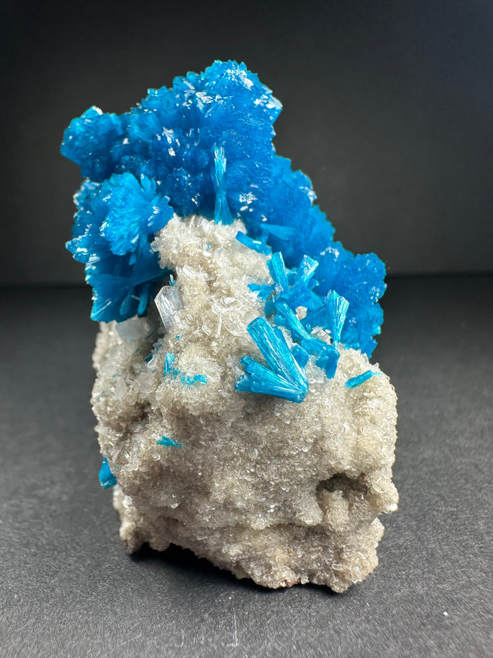 Bright blue cavansite over pale stilbite on gray rock matrix