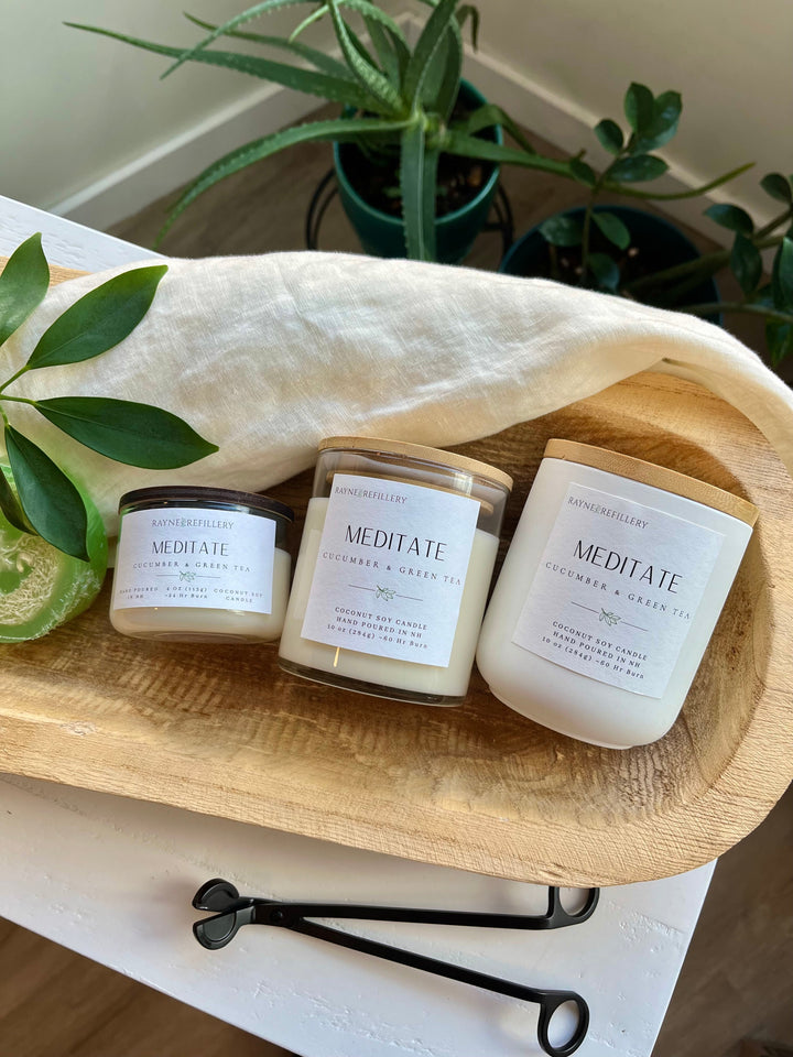 Set of three coconut soy candles in white glass jars with wood lids on tray