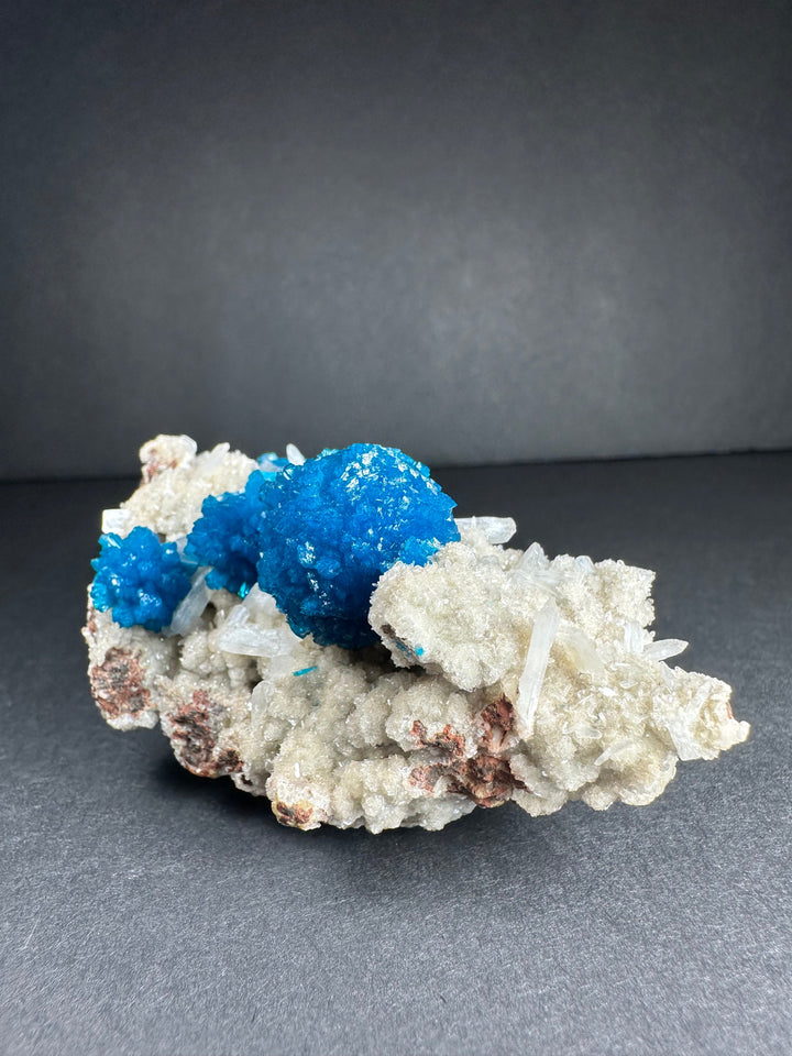 Cavansite and stilbite mineral specimen with bright blue crystal clusters on white matrix