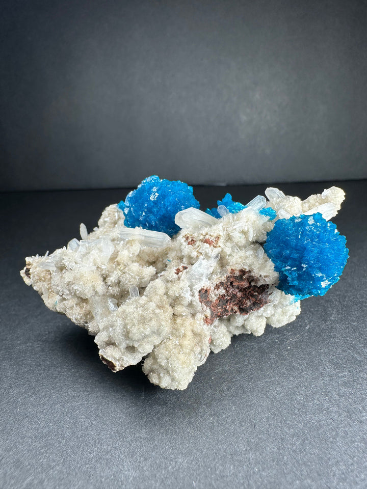 Cavansite and stilbite mineral specimen with blue crystal clusters on pale white matrix