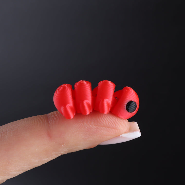 Red animal fidget toy with black oval eye and stacked fin-like segments