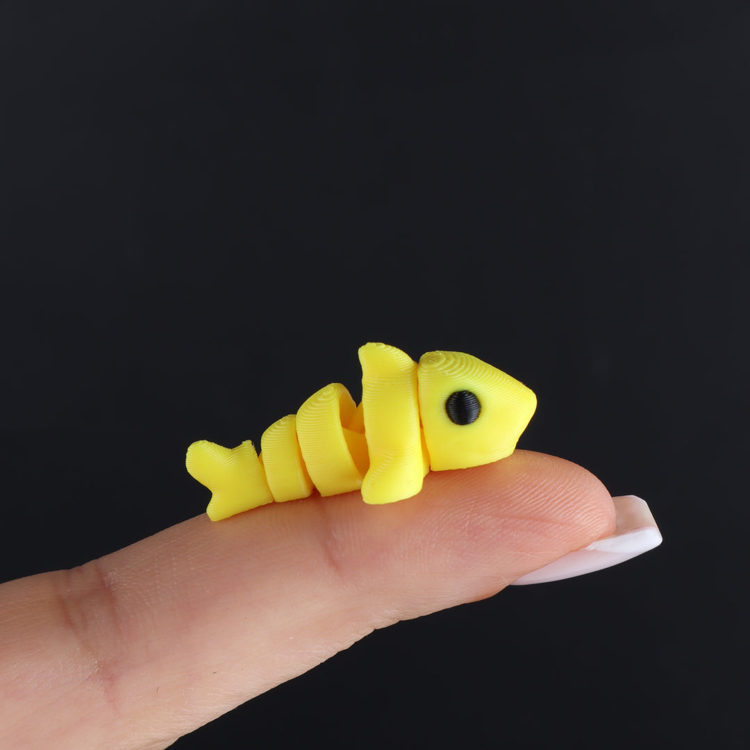 Yellow animal fidget toy with black oval eye and small tail fin segment