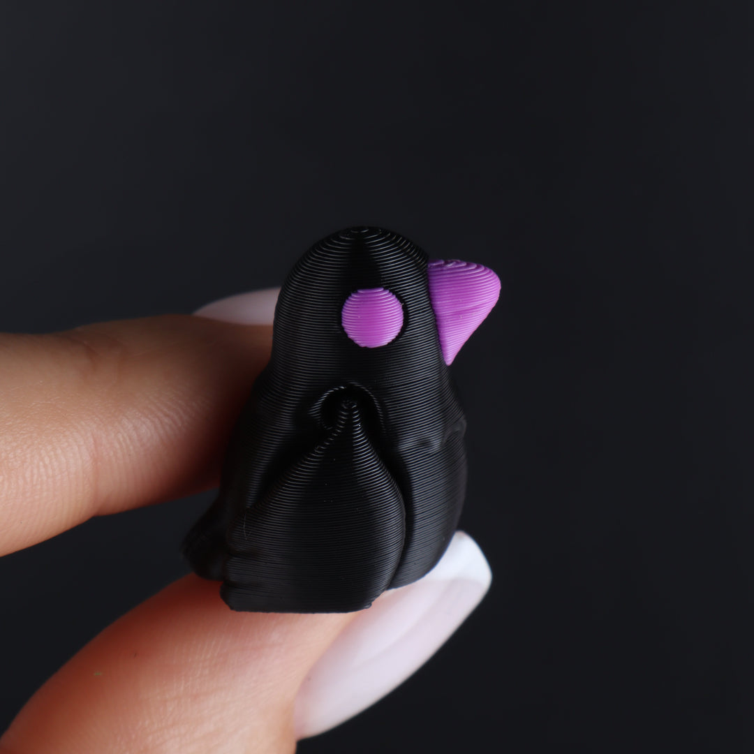 Black animal fidget toy with purple inner details and a rounded face