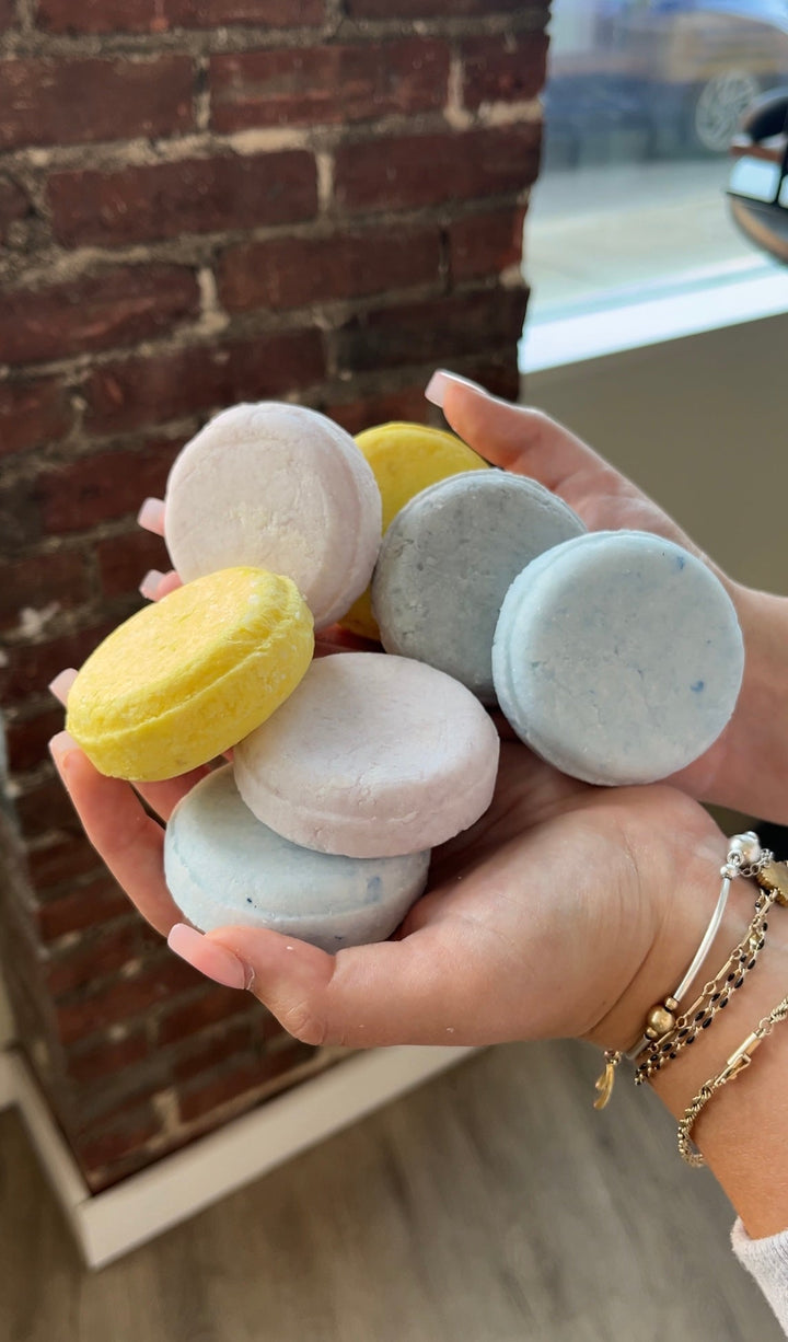 Assorted solid shampoo bars in pastel colors held in a hand