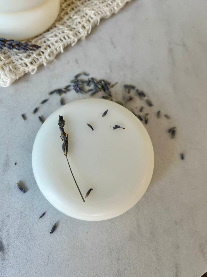 Solid conditioner bar with lavender buds on a white round disk
