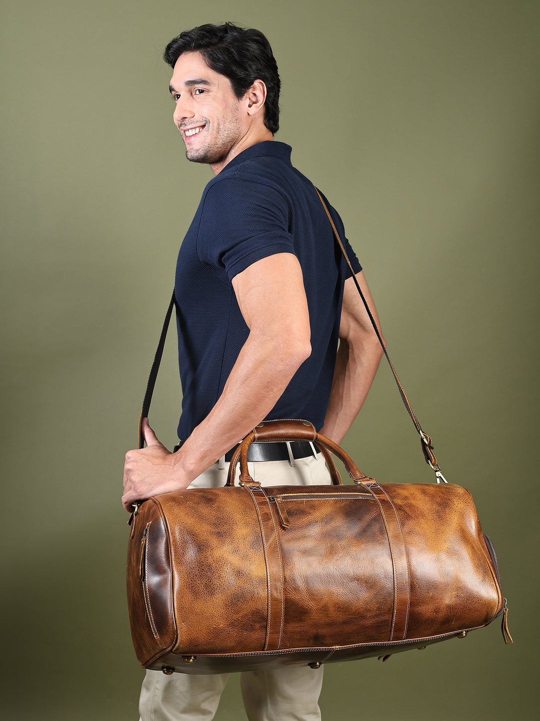 Brown leather duffel bag on shoulder with adjustable strap and front zip