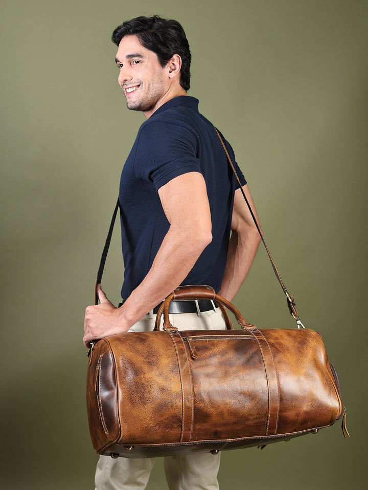 Brown leather duffel bag on shoulder with adjustable strap and front zip