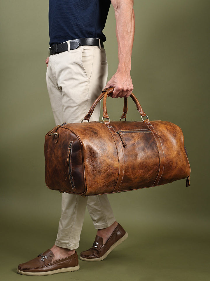 Brown buffalo leather duffel bag held by man, with dual handles and front zipper